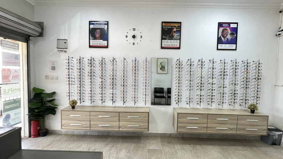 Wall-mounted eyeglass frame displays and fitting mirror at Lead Opticals in Oyarifa, Accra